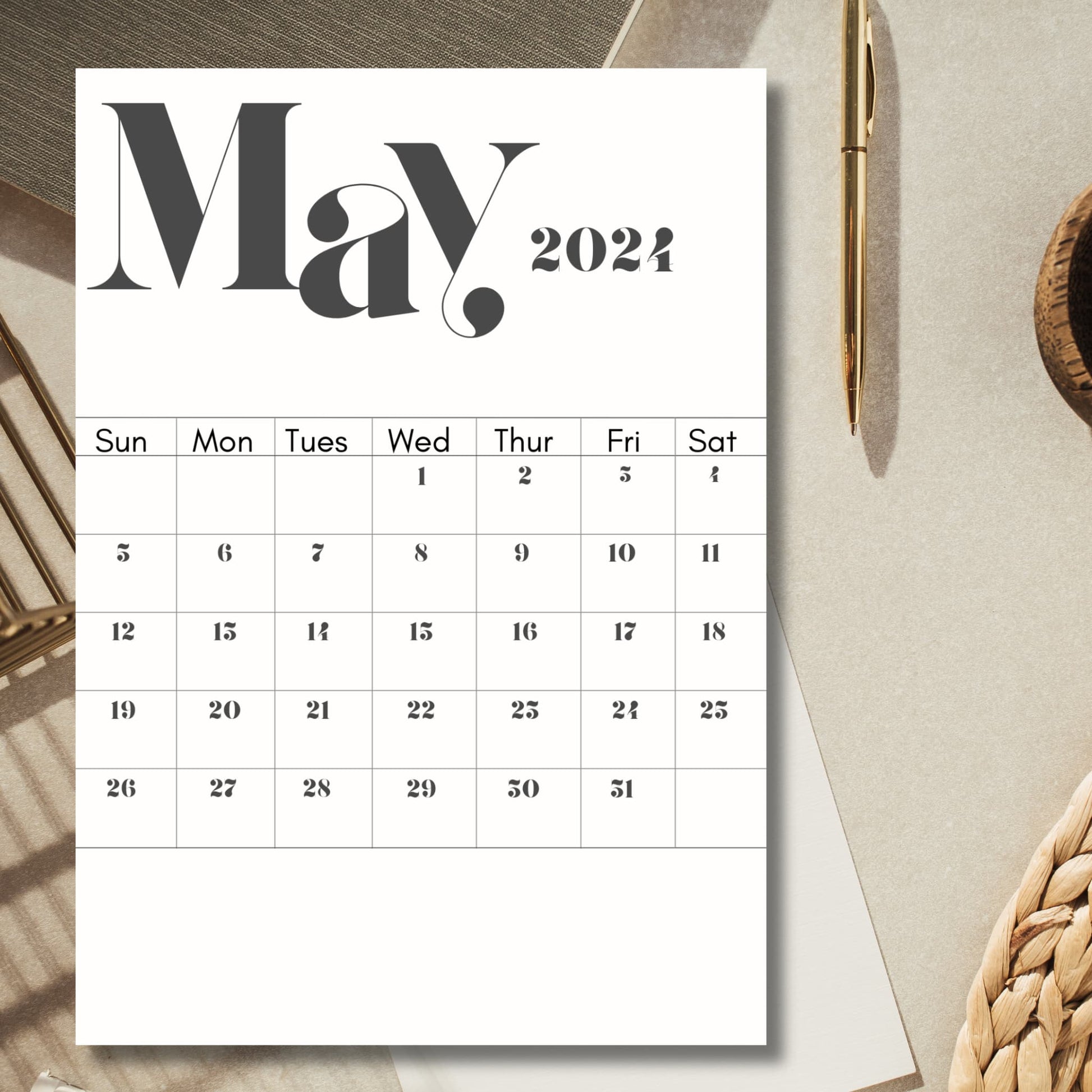 2024 May calendar page print on a table with pen and laptop.