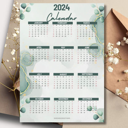Modern aesthetic 2024 full year calendar on a table with envelope and small white flowers in the background.