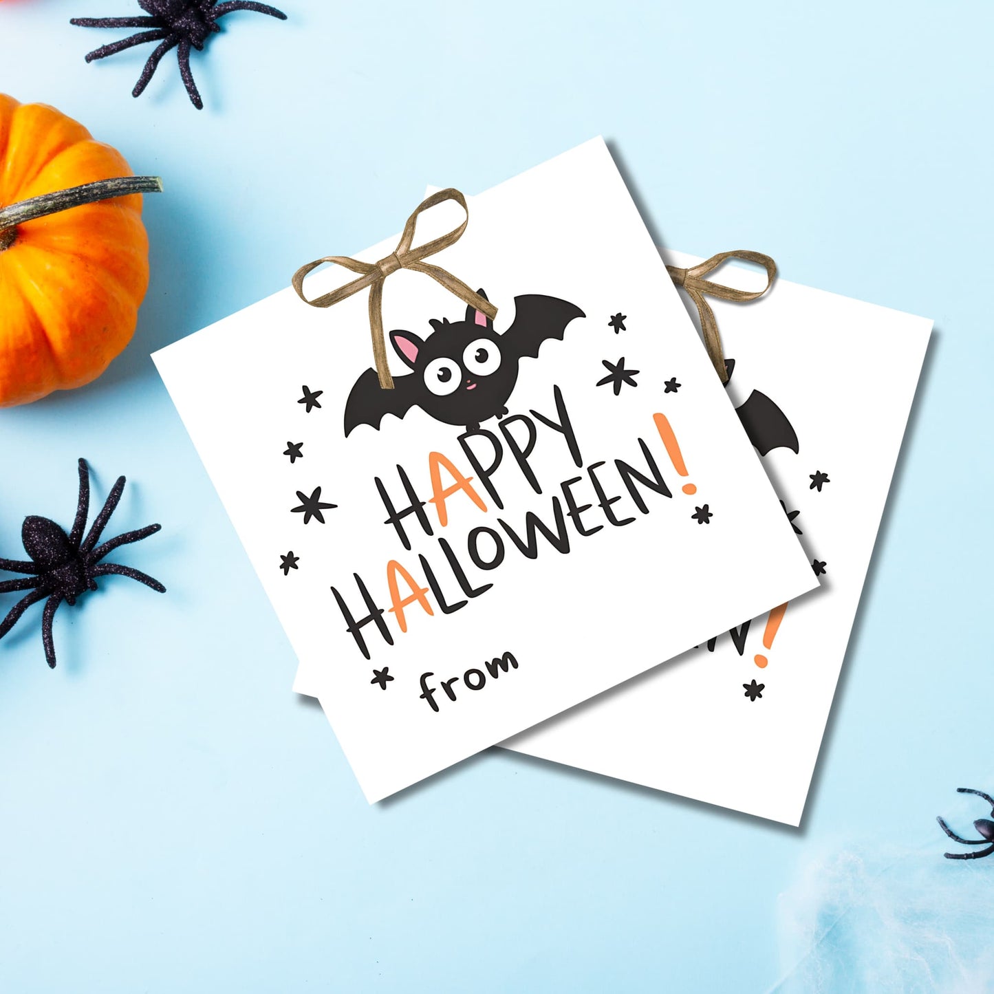 Halloween favor tags with charming bat design, arranged on light blue background with festive Halloween decorations