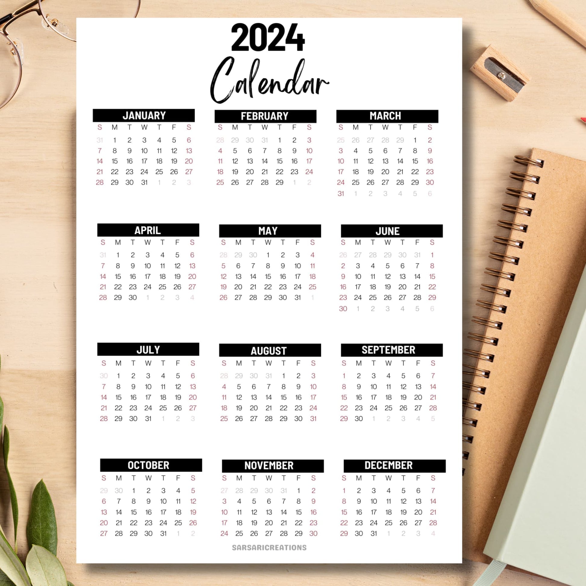 Office essential 2024 calendar on light brown wooden desk with school supplies like notebook, pencil, sharpener.