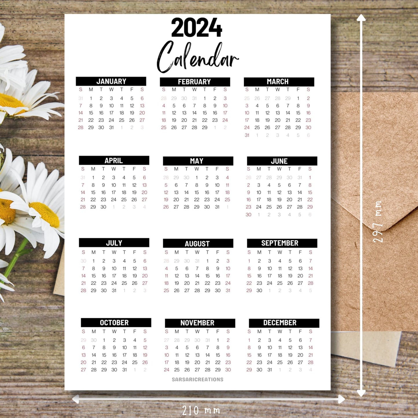Office essential 2024 calendar on brown wooden desk with white flowers and size guide.