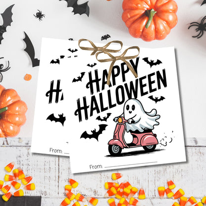 White Halloween gift tags with retro ghost on pink scooter, displayed with pumpkins and spooky decorations for costume party favors