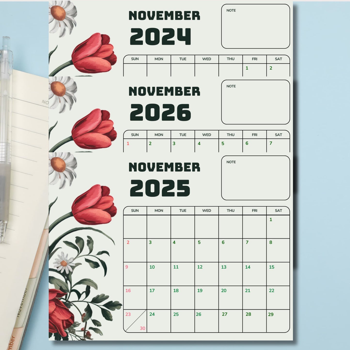 Three-year November calendar with watercolor red tulips and white daisies, featuring note sections and color-coded dates on ivory background, displayed on blue surface