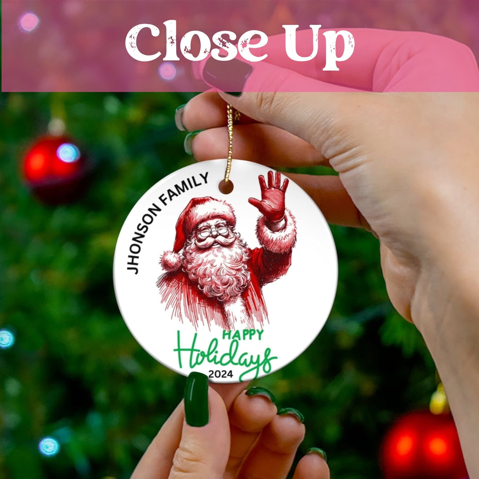 Close-up view of personalized Santa Christmas ornament held against decorated tree, showing crisp red artwork and green text details.