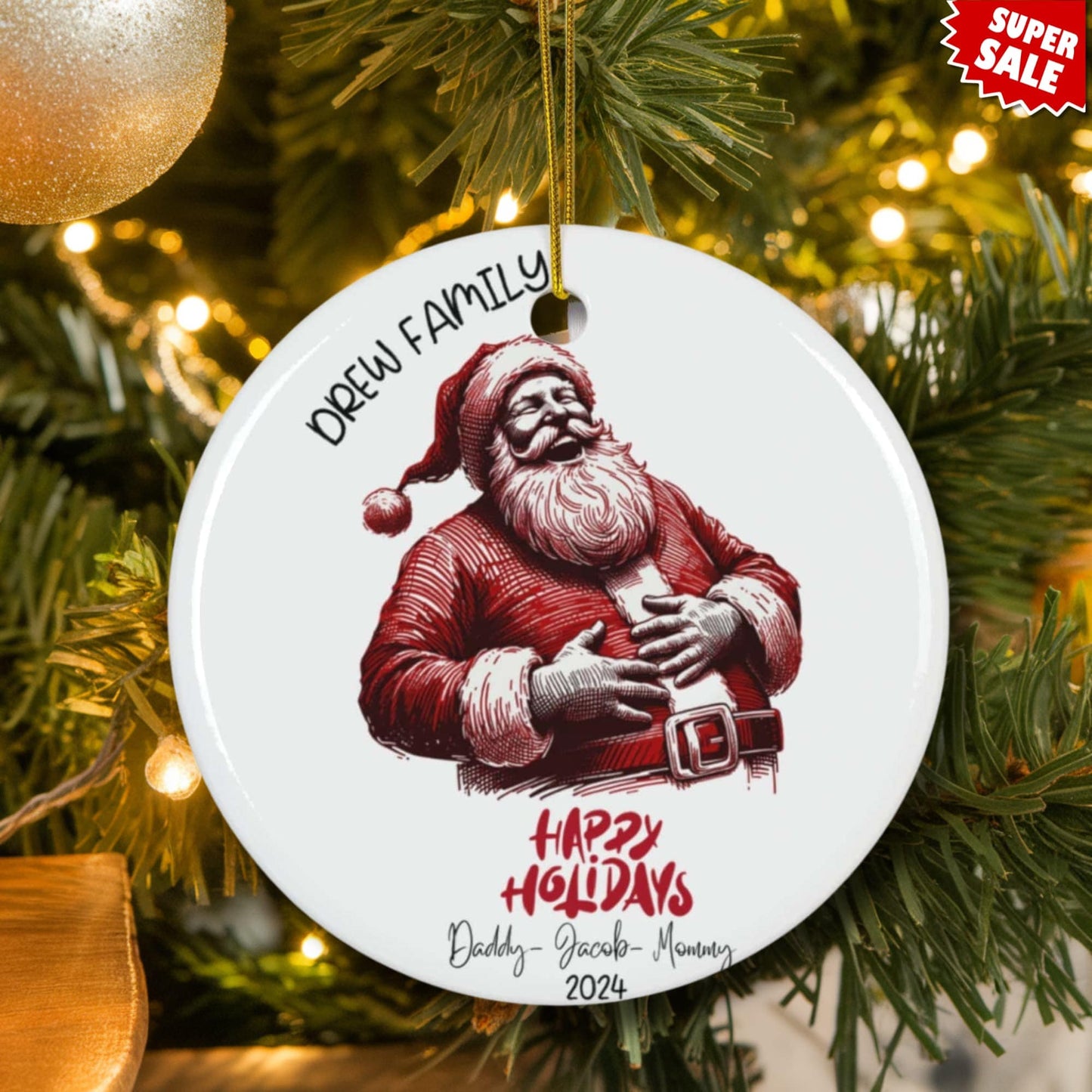 Drew family ceramic ornament displayed on lit Christmas tree with gold baubles, featuring jolly Santa design and Super Sale promotion.