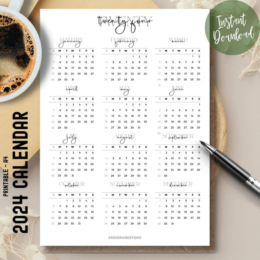 Script font style 2024 full year calendar printed page on brown desk with coffee cup on left and pen on right.