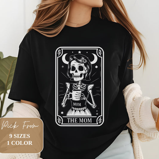 Woman wearing black t-shirt with white skeleton 'The Mom' tarot card design. Skeleton holds coffee mug. Available in 9 sizes, 1 color.