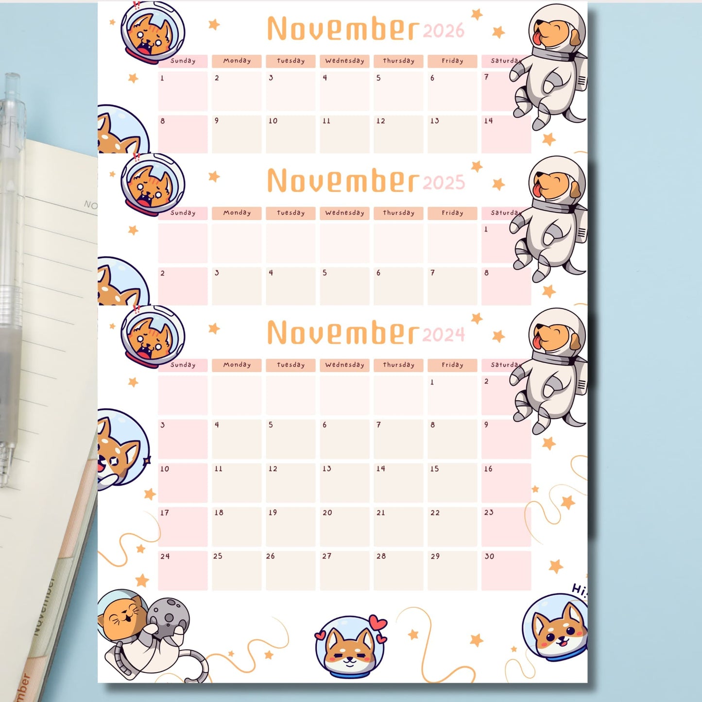 Three-year November calendar set with kawaii space puppies in astronaut helmets, featuring pink and peach color blocks and scattered stars on light blue background.