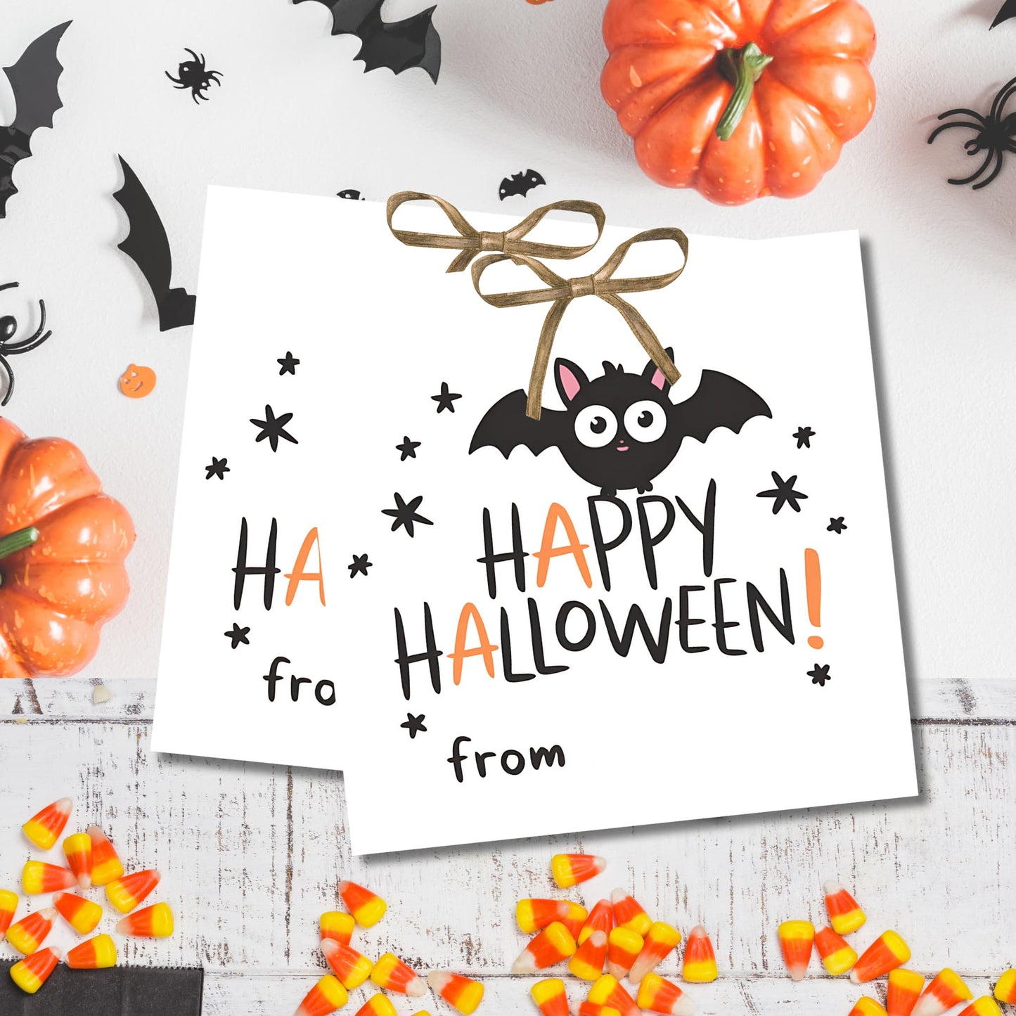 White Halloween gift tags with adorable bat character, displayed with pumpkins and spooky decorations for costume party favors